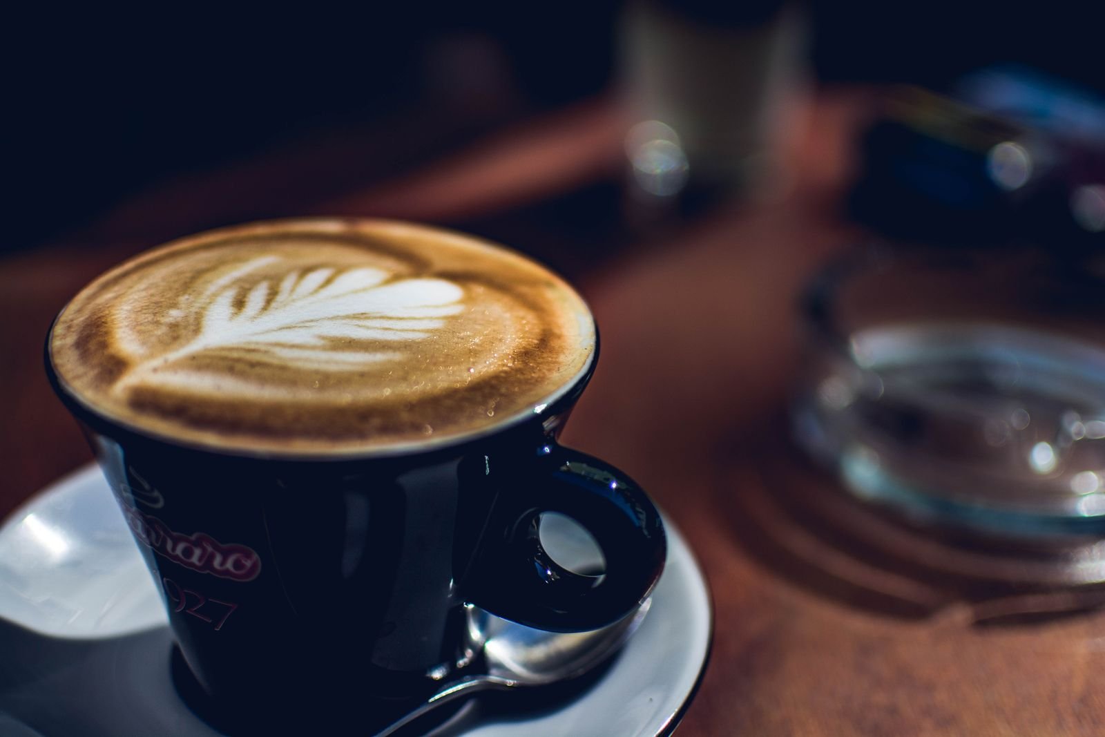 A beautifully crafted latte with leaf art in a cozy café setting, perfect for coffee lovers