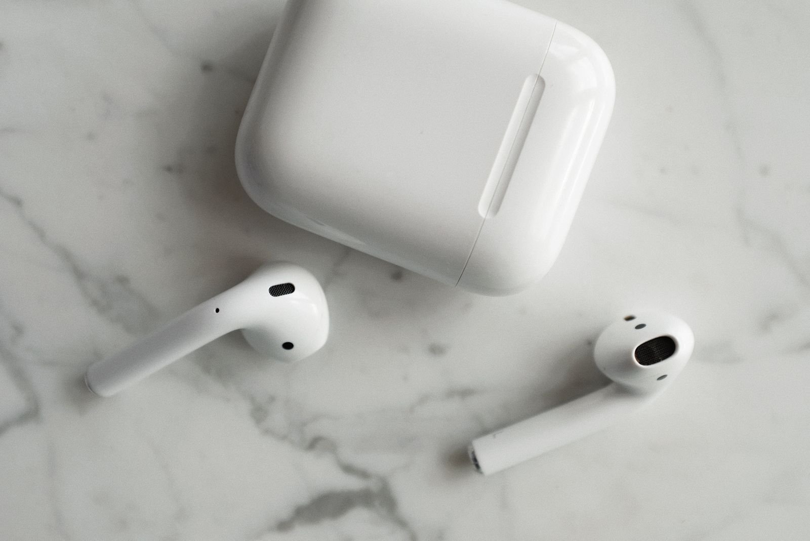 High-quality image of wireless earbuds and charging case on marble surface, showcasing modern technology