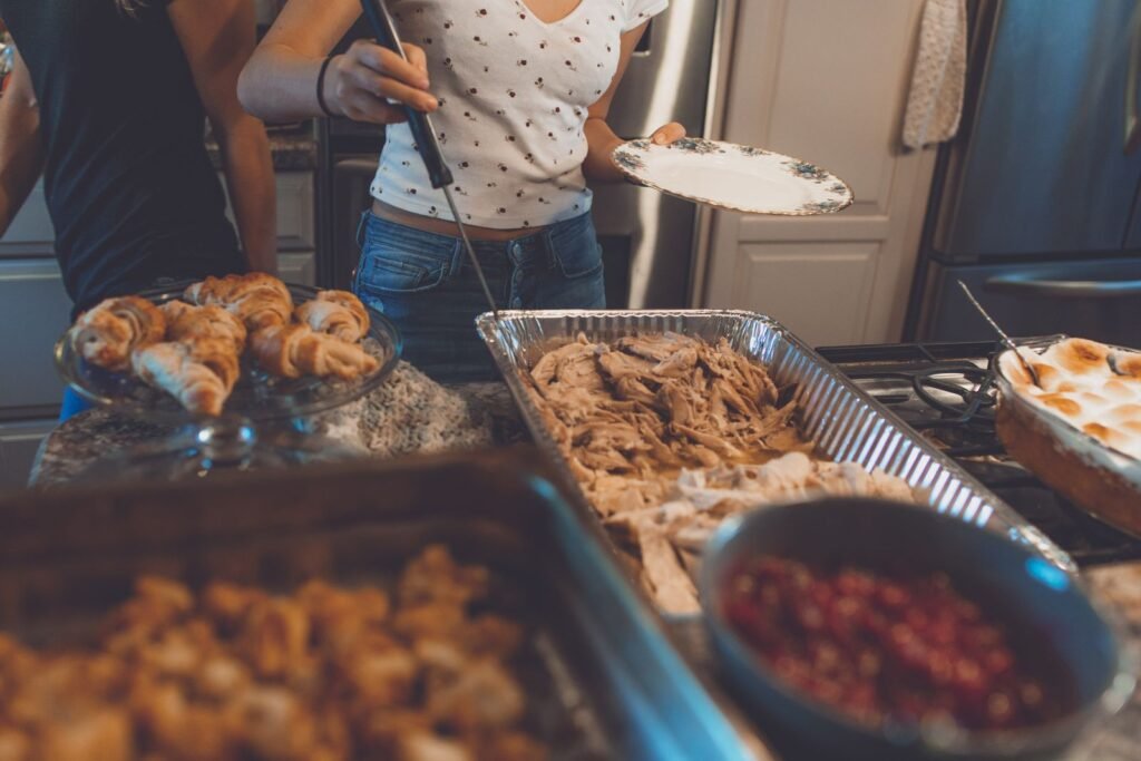 Warm indoor scene of a Thanksgiving dinner buffet featuring turkey, croissants, and side dishes