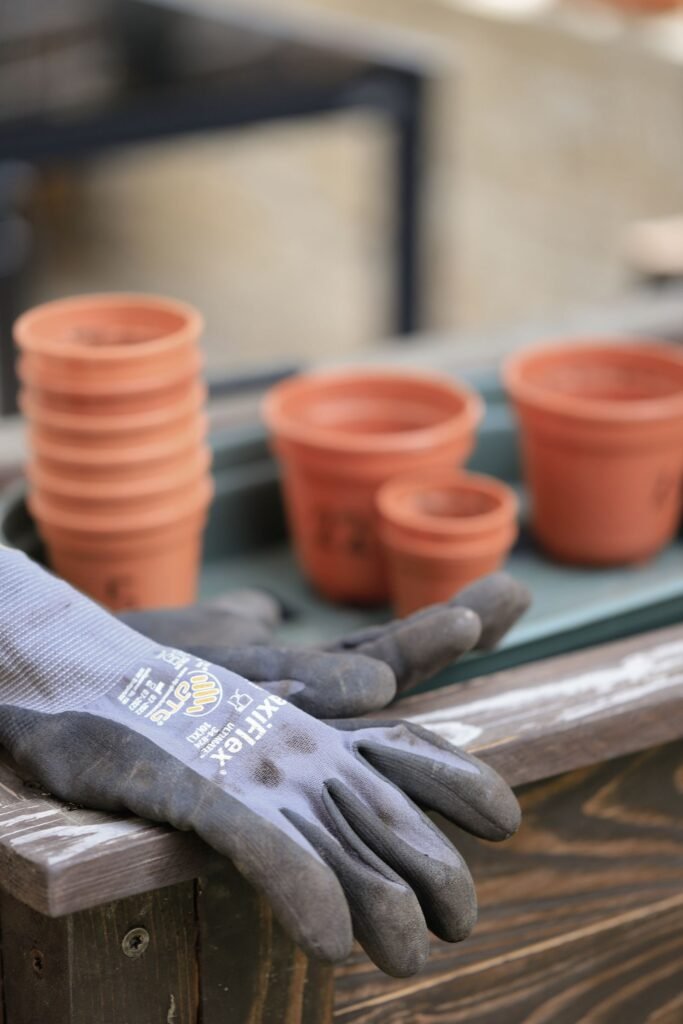 Gardening gloves resting beside stacked terracotta clay pots on a potting bench