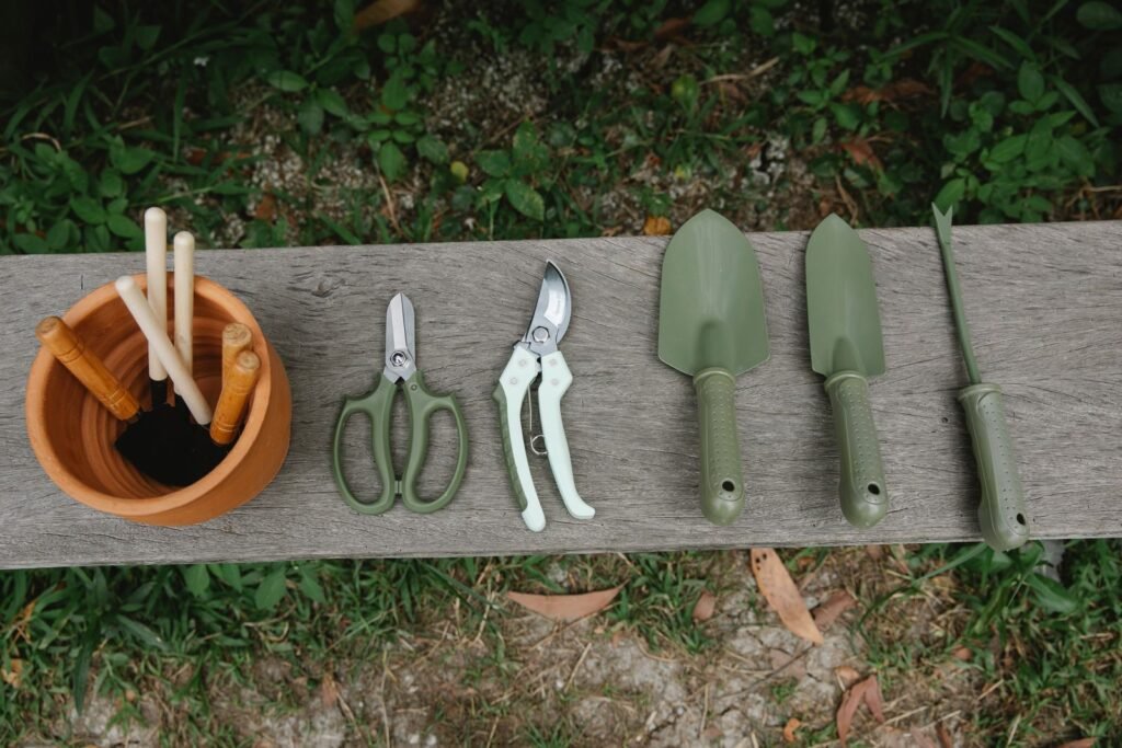 Garden hand tools and a pot of tools lined up on a wooden bench in the yard
