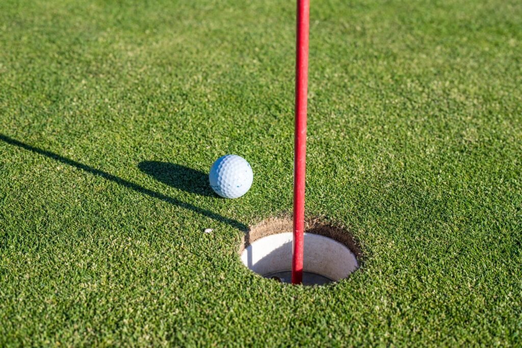 A golf ball resting near the hole on a putting green