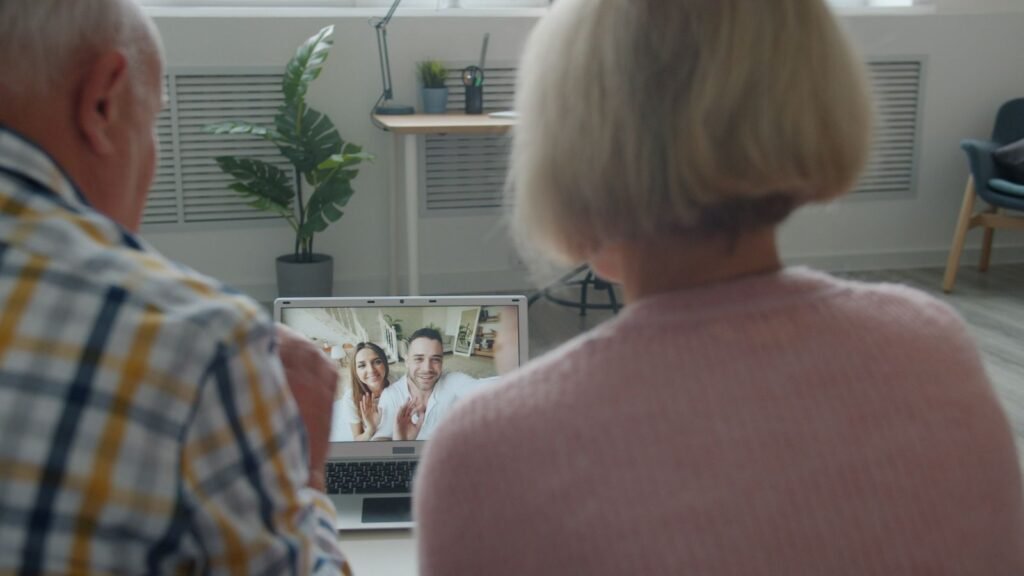 Grandparents on a video call with family on a laptop at home