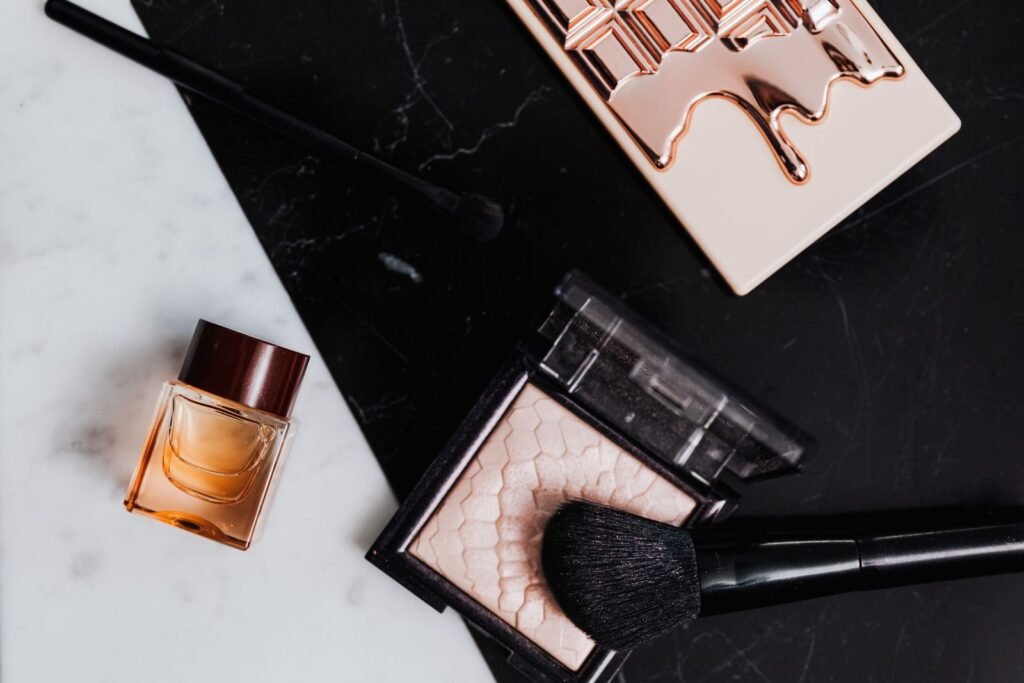Beauty products including eyeshadow, lipstick, and perfume on marble