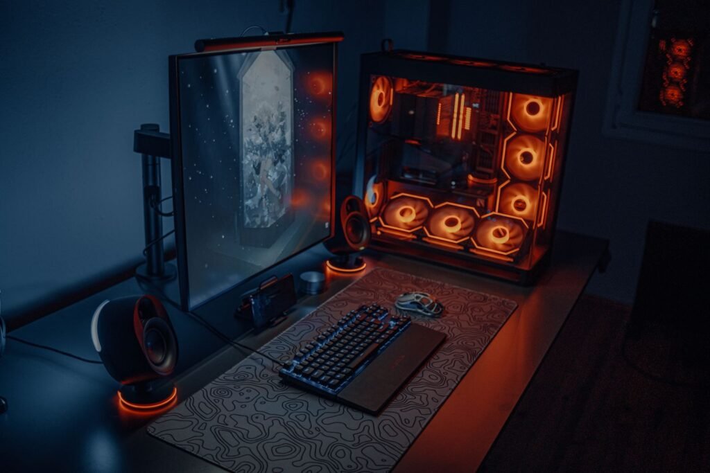 Sleek gaming desk setup featuring RGB lighting, large monitor, and gaming PC with glowing fans