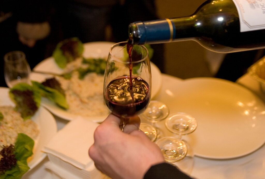 Red wine being poured into a glass at a dinner table
