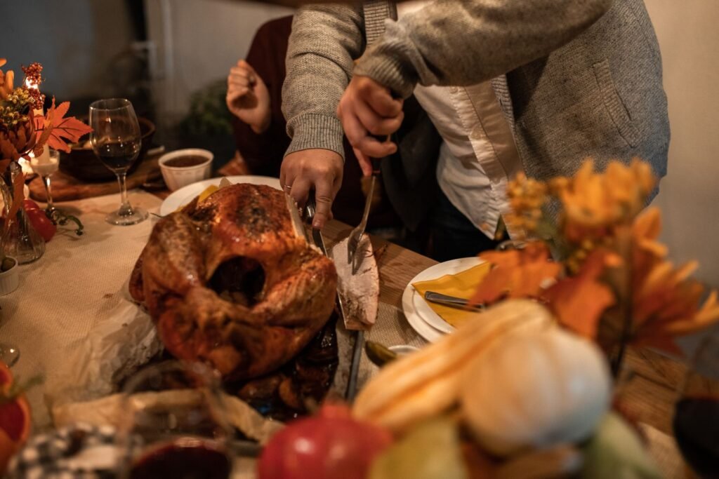 Close-up of a festive Thanksgiving table with roasted turkey being carved