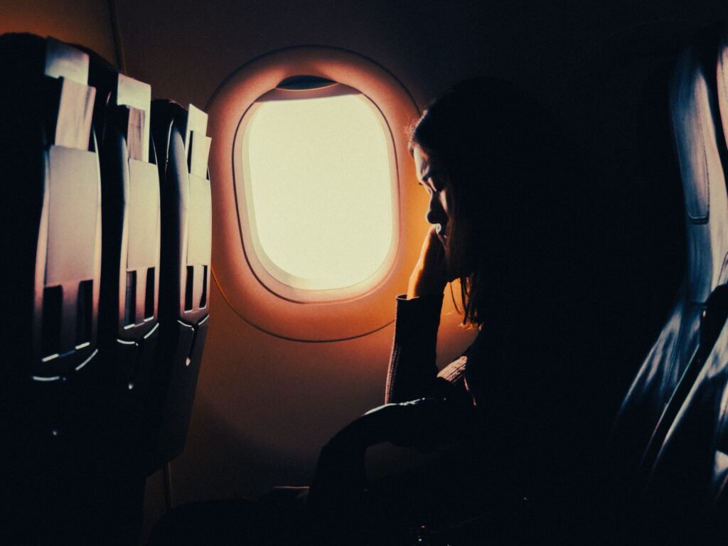 Silhouette of a traveler resting by an airplane window seat during a flight