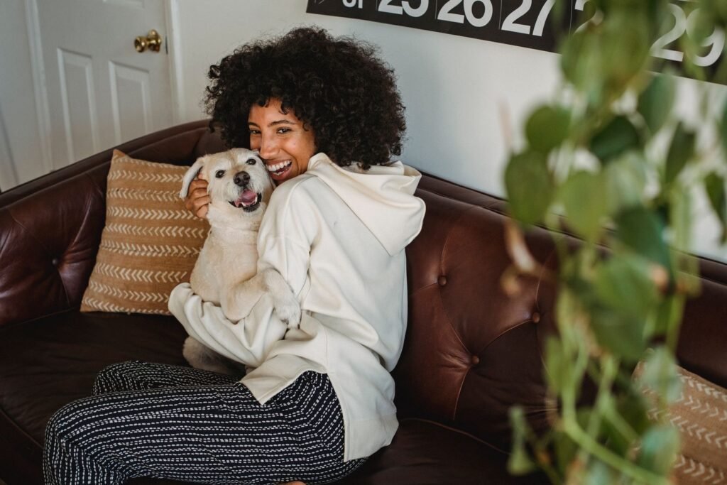 Smiling woman hugging her dog on a leather sofa at home