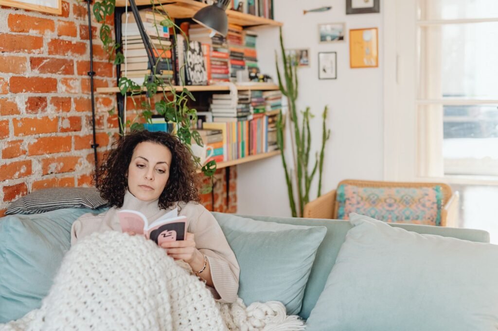 Woman relaxing with a book on a cozy sofa in a home library