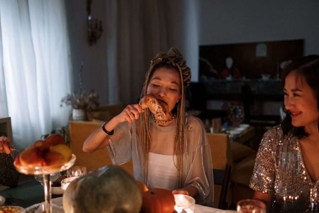 Women enjoying a festive dinner with laughter and delicious food around a cozy table indoors